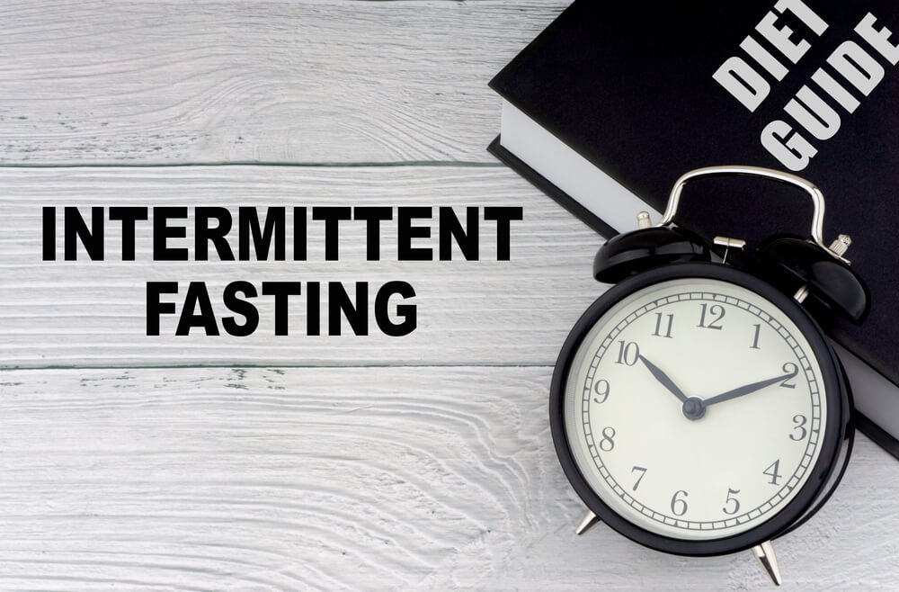 Intermittent fasting words with clock on the table