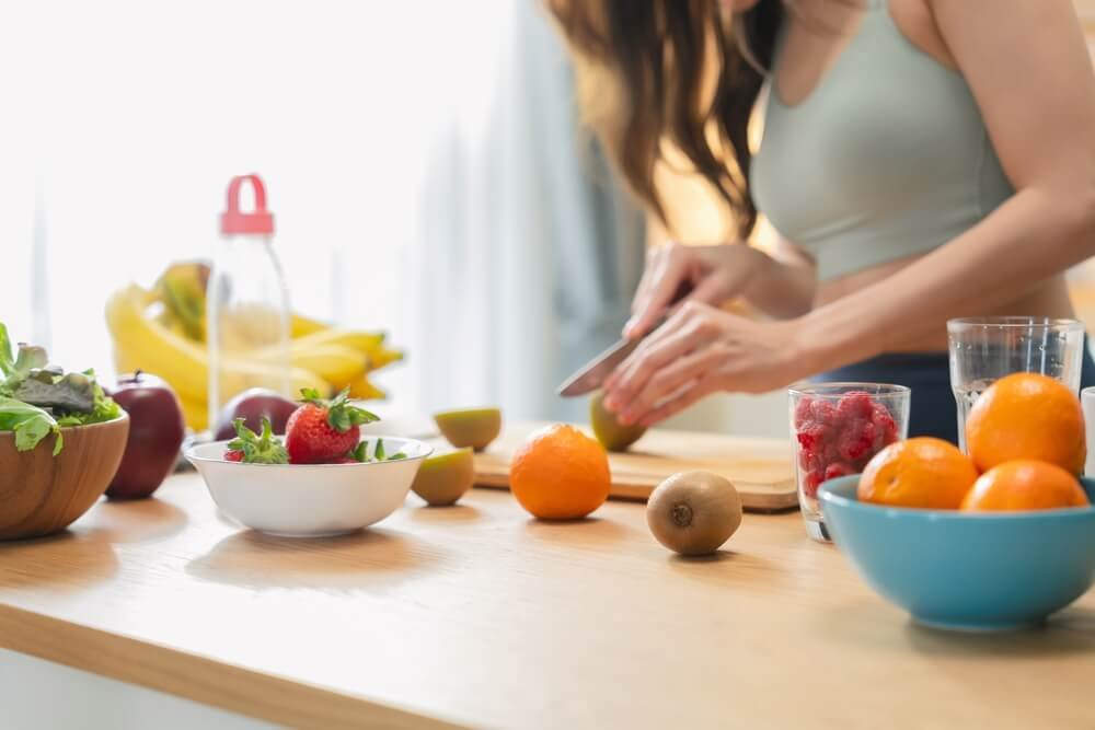 a woman cutting some fruit in the kitchen